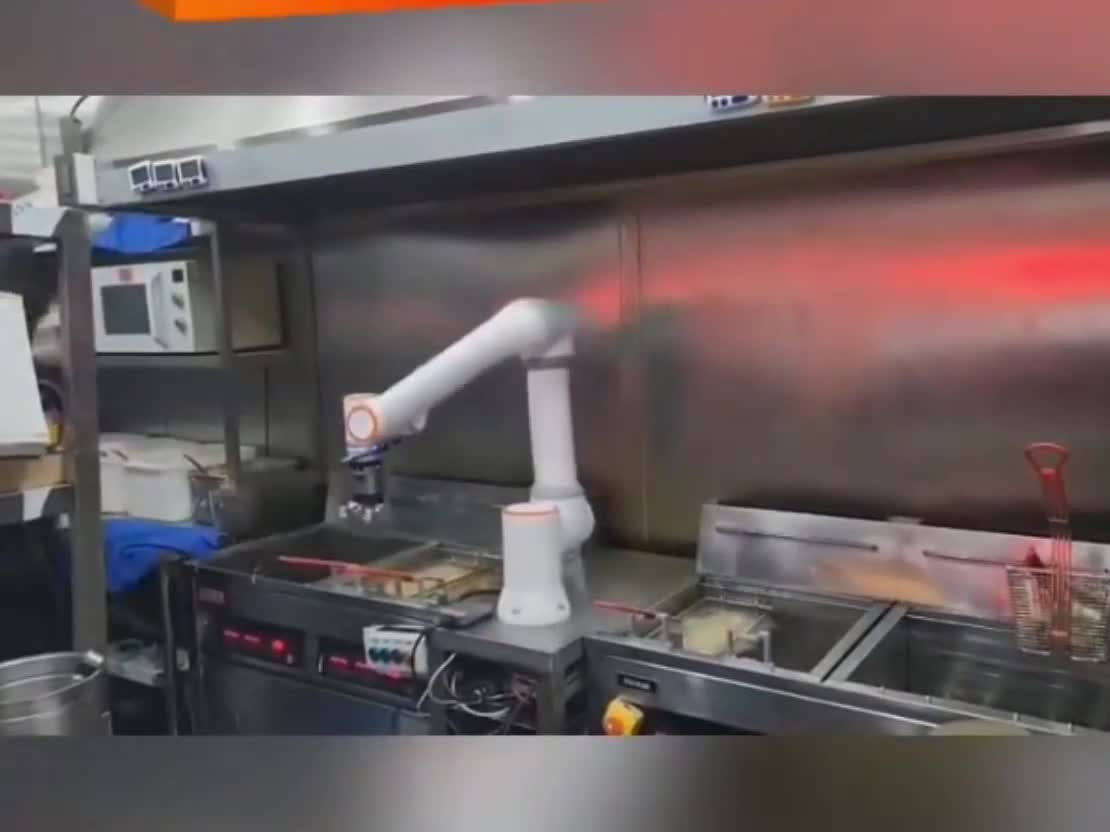 ArmMate cobot holding a basket beside a fryer.
